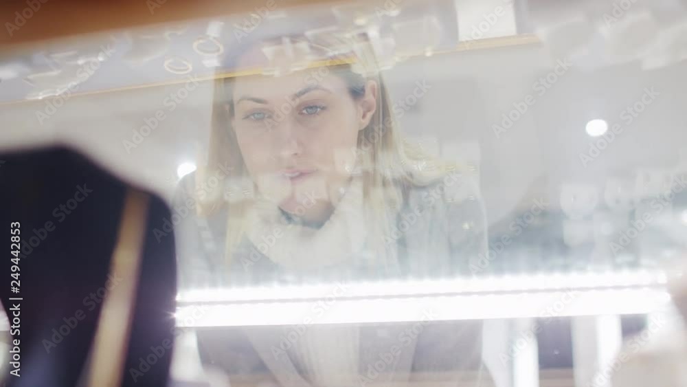 Woman looking at jewellery in the store as shop assistant advises her Woman looking at jewellery in the store as shop assistant advises her