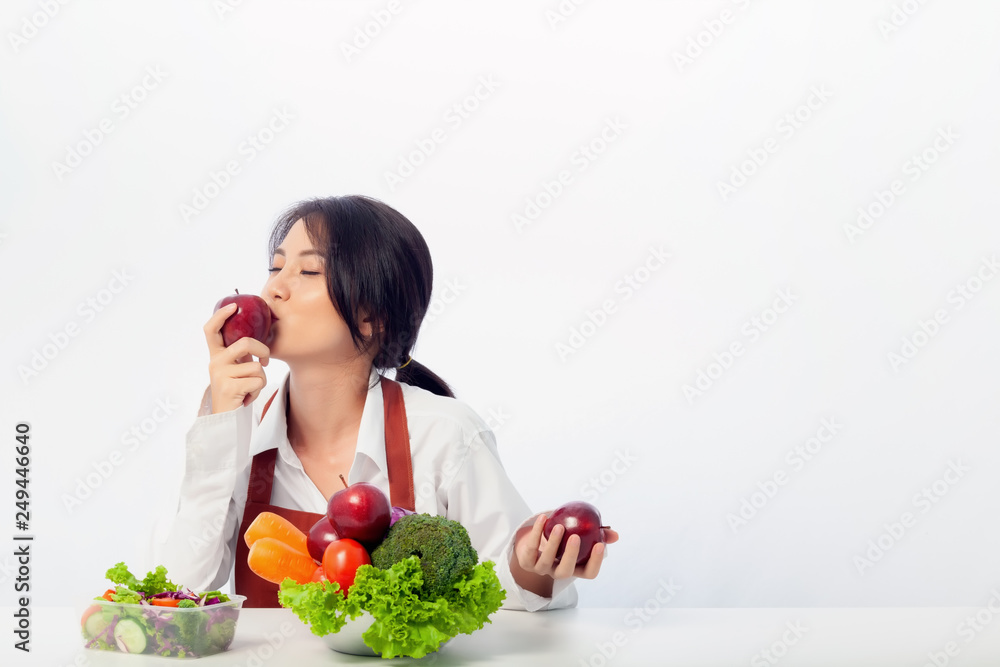 Asian young woman wearing an apron coat and holding fresh ingredients for healthy salad. Asian young woman wearing an apron coat and holding fresh ingredients for healthy salad.