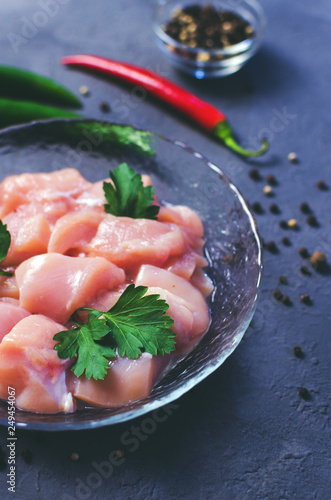 Raw chicken cubes in bowl on dark stone table. Breast cubes. Soft selective focus.