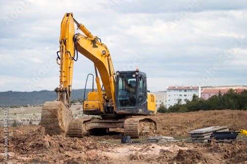 Yellow excavator at construction site into mud with sky background