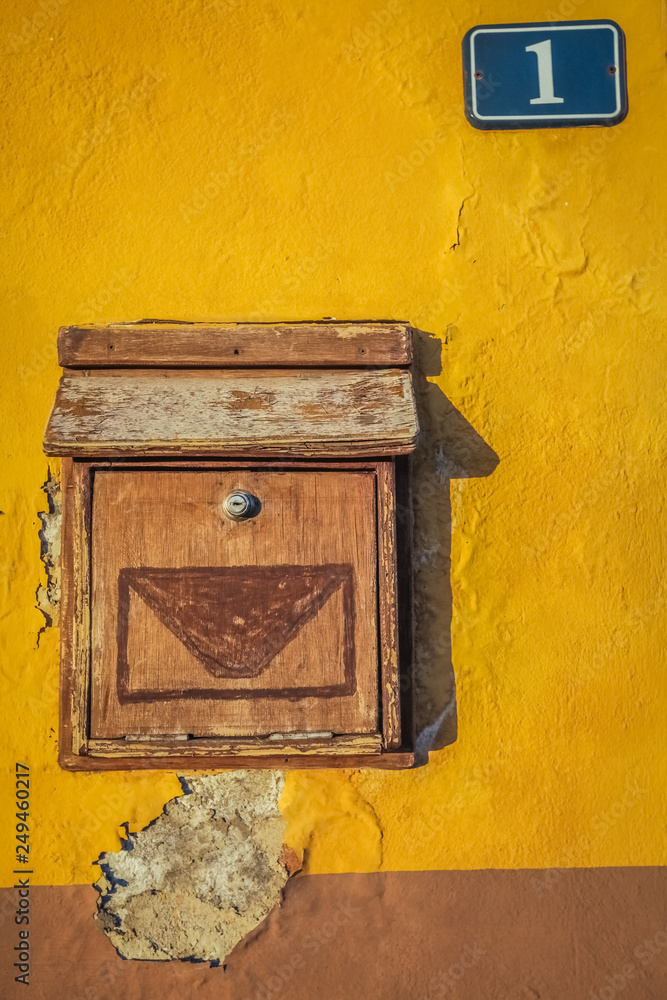 Old wooden letterbox on a yellow wall