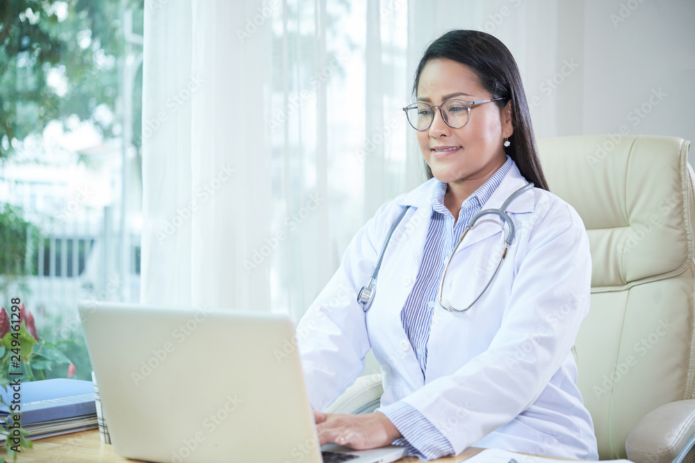 Smiling doctor working on laptop Smiling doctor working on laptop