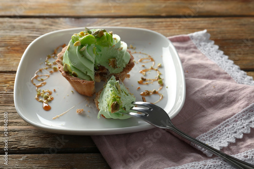 Plate with tasty pistachio tartlet on table
