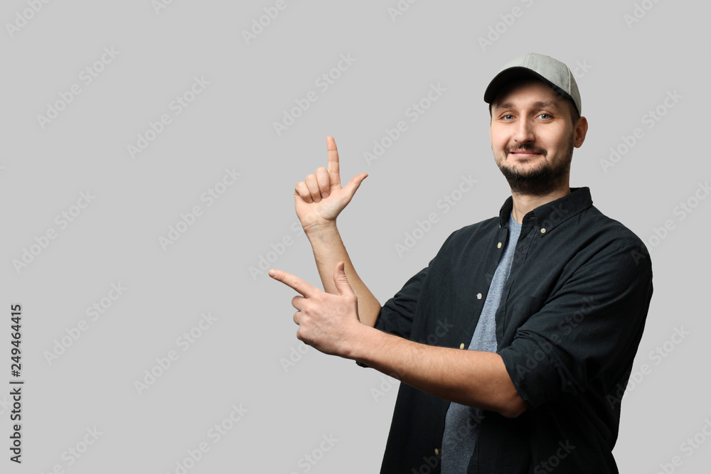Fashionable white man with beard and cap shows finger on empty space for text. Look over there, pointing away. Fashionable white man with beard and cap shows finger on empty space for text. Look over there, pointing away.