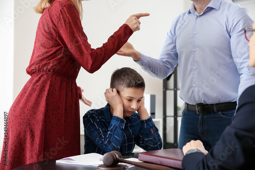 Fotografie Sad little boy with his quarreling parents in lawyer's office