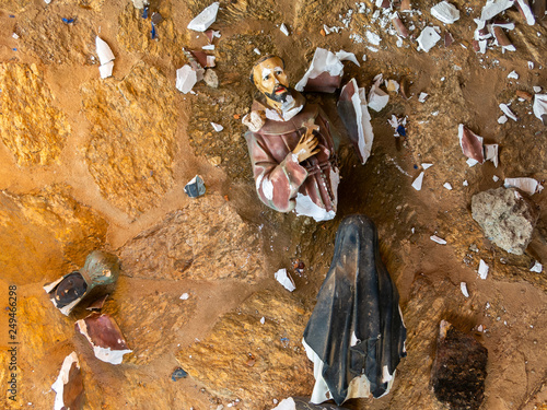 Broken vandalized plaster catholic plaster statues in the ground photo