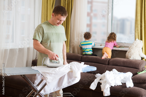 Foto Unhappy man at home ironing clothes  in laundry room at home