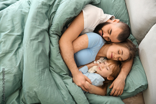 Happy family sleeping in be...