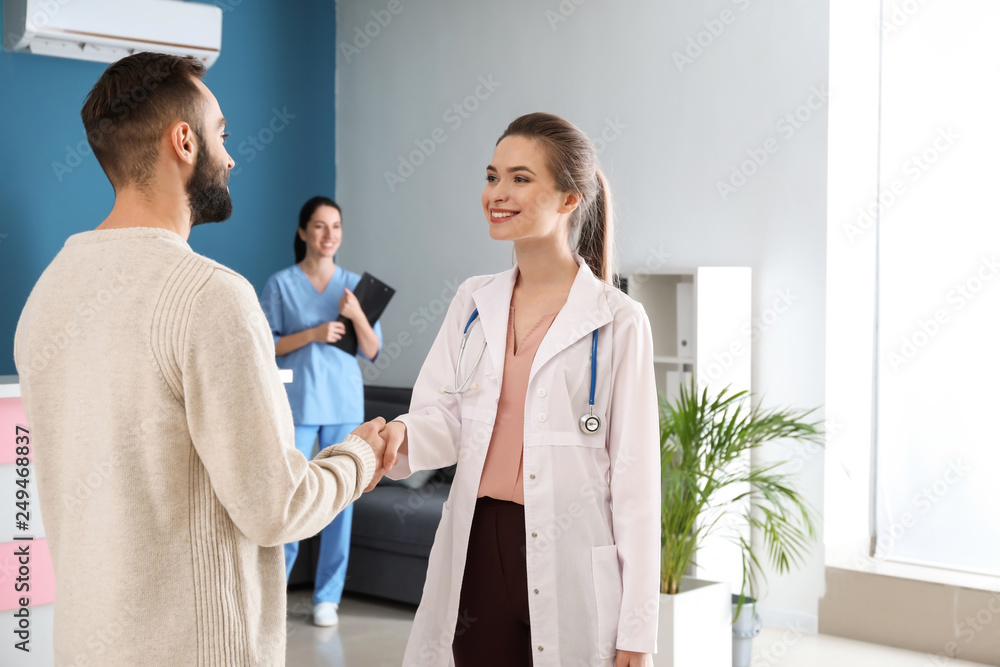 Fototapeta premium Male patient and doctor shaking hands in clinic