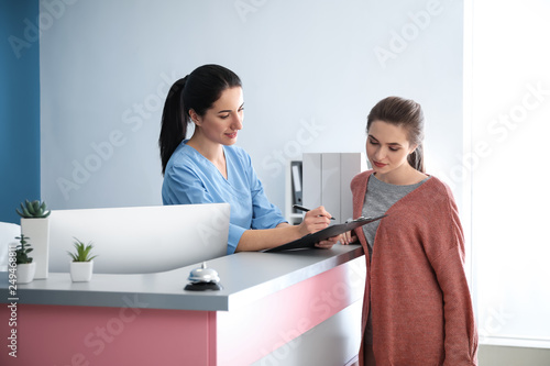 Fényképezés Young woman near reception desk in clinic