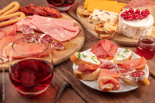 Wine tasting and pairing. A wineglass with charcuterie, sandwiches and a cheese platter on a dark wooden background