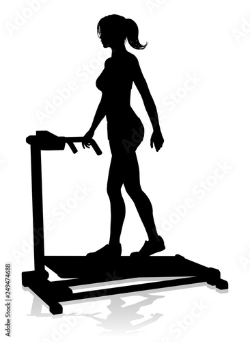 A woman in silhouette using a treadmill running machine piece of gym fitness equipment 