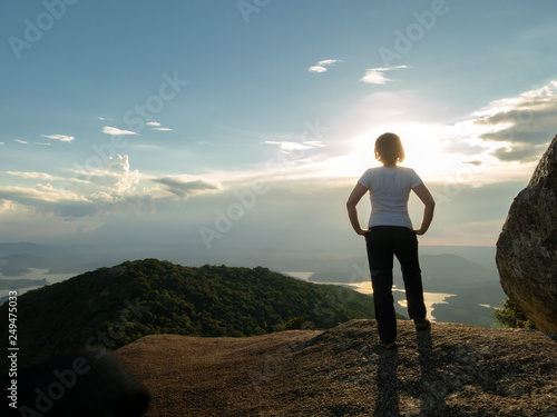 Unrecognized people - girl in mountain summit top looking landscape and dam reservoir - backlight sunset