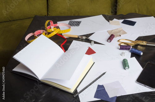 Lot of designer`s tool on the black table in his office,green sofa.Concept of designer`s work