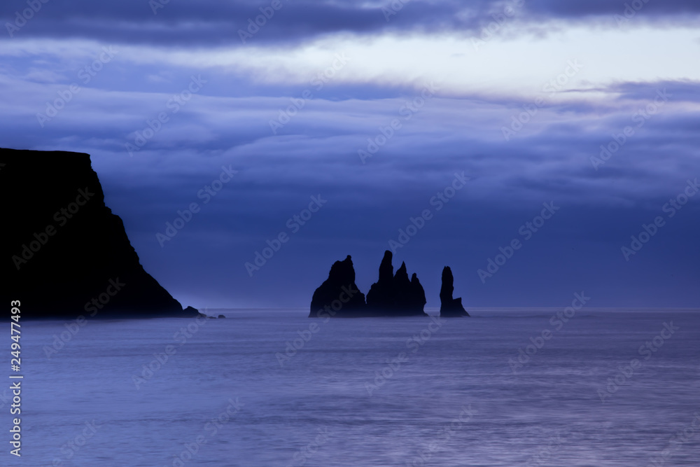 Famous basalt sea stacks of Reynisdrangar, rock formations on the black sand of Reynisfjar beach, view not far from Vik, a small village in southern Iceland. Troll Fingers