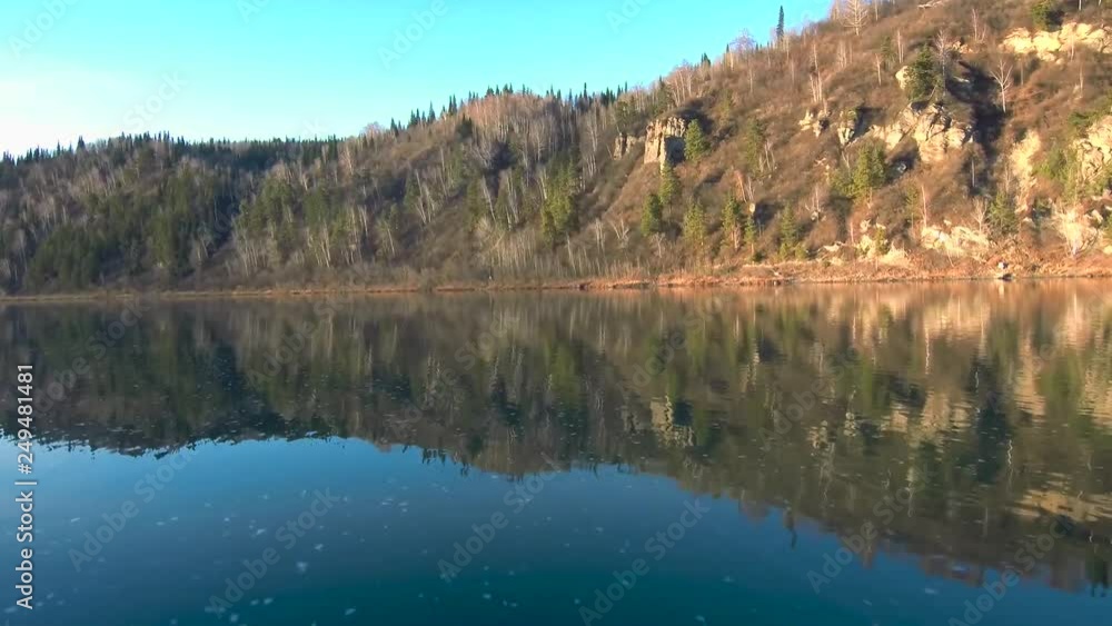 rocky shore. Flight over the river. Reflection of a mountain on the water. Autumn landscape. River at the foot of the mountain. Water surface rocky shore. Flight over the river. Reflection of a mountain on the water. Autumn landscape. River at the foot of the mountain. Water surface