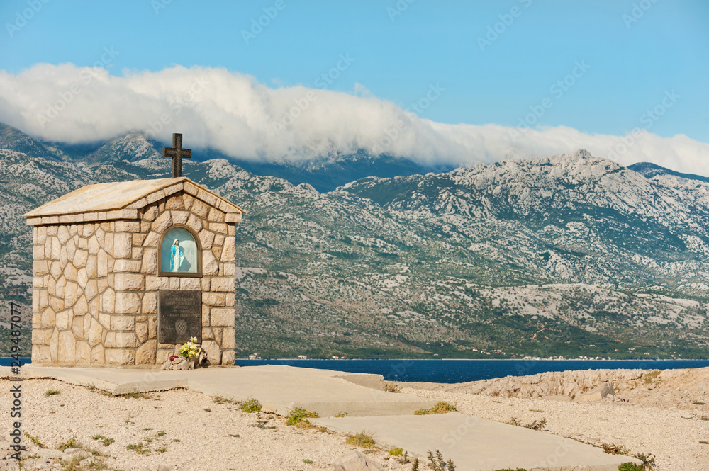 Small chapel dedicated to Saint Mary on the island of Pag with Velebit mountains on background, Croatia