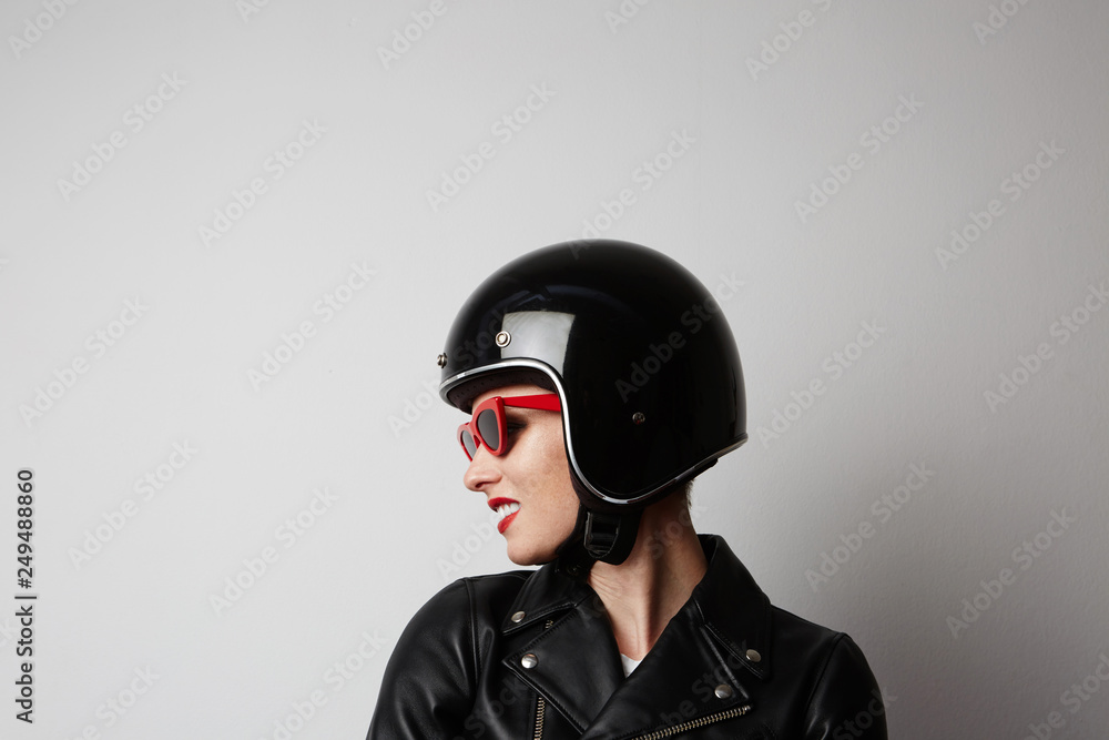 Fabulous woman with red lips in black leather jacket smiling looking at camera over white background. Fashion, glamour and transportation concept Fabulous woman with red lips in black leather jacket smiling looking at camera over white background. Fashion, glamour and transportation concept