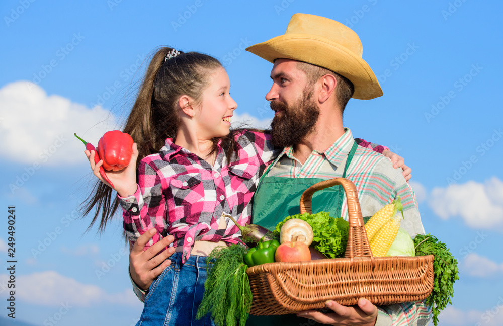 Only organic and fresh harvest. Man bearded rustic farmer with kid. Father and daughter hold basket harvest vegetables. Gardening and harvesting. Family farm concept. Farmer family homegrown harvest