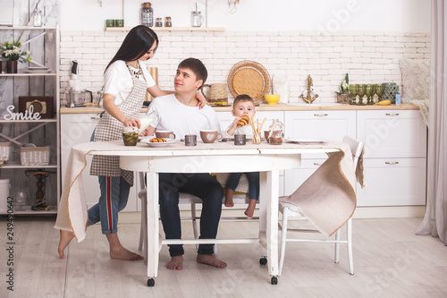 Happy family having breakfast together. Young family eating at the table on the kitchen. Mom, dad and little baby eating.