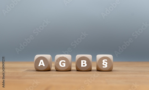 Würfel mit Abkürzung AGB und Paragraph Symbol auf Holztisch vor grauen Hintergrund. photo