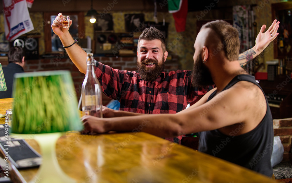 Strong alcohol drinks. Alcohol addiction. Friends relaxing in pub. Men drunk relaxing at pub having fun. Hipster brutal man drinking alcohol with friend at bar counter. Men drinking alcohol together