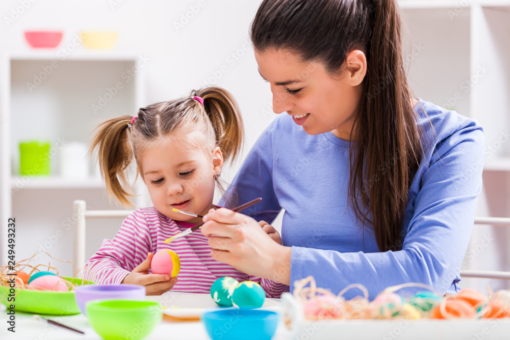 Fototapeta premium Happy mother and daughter coloring eggs for Easter. 