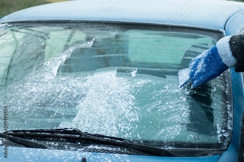 closeup of hand of woman scraping frost on the windscreen of car