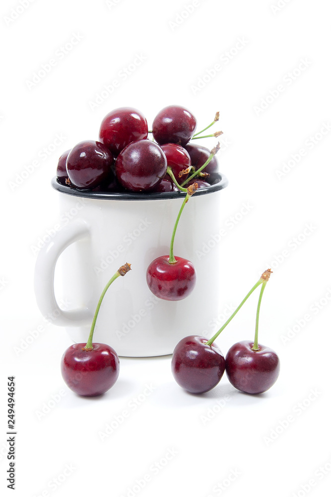 White cup with red sweet cherry isolated on a white background.. White cup with red sweet cherry isolated on a white background..