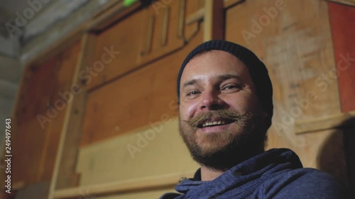a guy with a beard and mustache in a knitted hat laughs