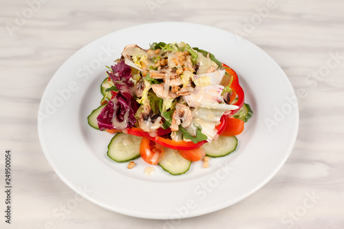 Vegetable salad with corn and mushrooms on a white plate on the table.