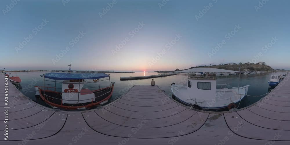 360 VR Video. Marine scene with harbour and boats tied up. Man sitting on the pier and looking at sunset over the sea. Nea Kallikratia, Greece 360 VR Video. Marine scene with harbour and boats tied up. Man sitting on the pier and looking at sunset over the sea. Nea Kallikratia, Greece
