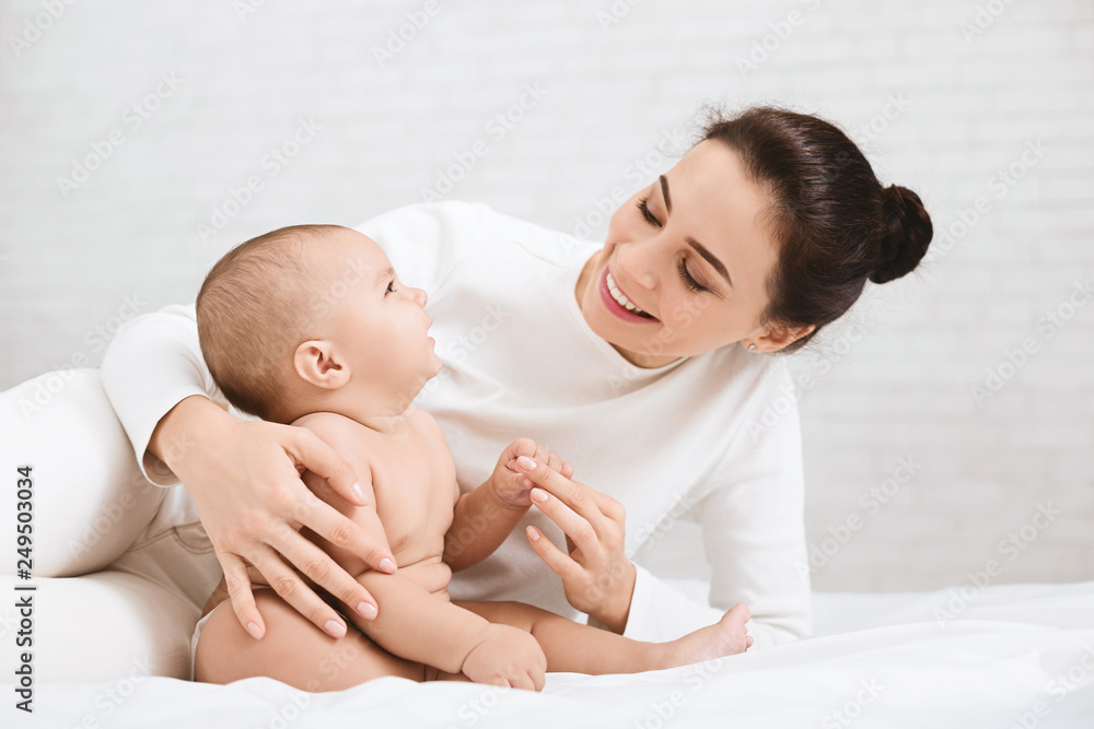 Mother playing with her baby in bedroom. Mother playing with her baby in bedroom.