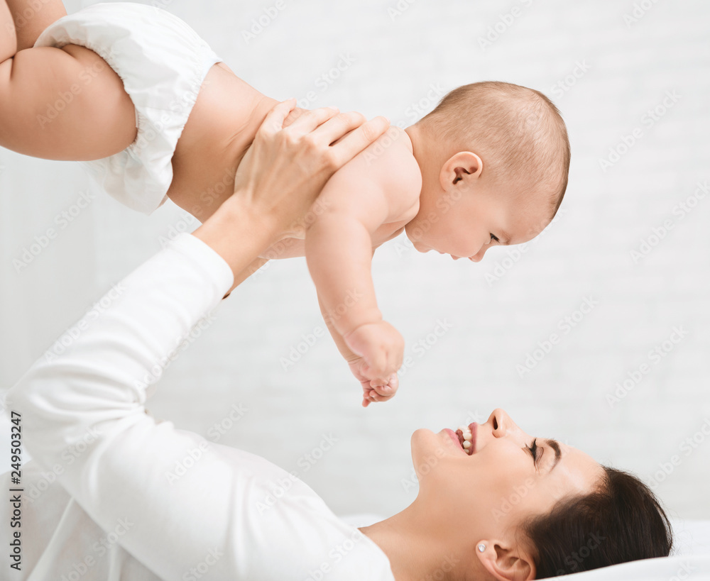 Young mom holding her happy baby in air Young mom holding her happy baby in air