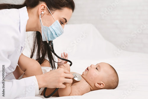 Pediatrician examining lungs of baby with stethoscope photo