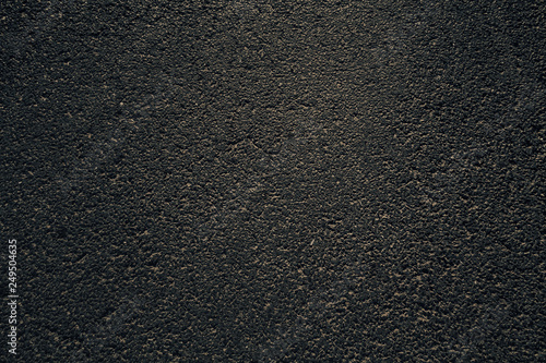 Dark asphalt texture on a sunny and hot summer day.