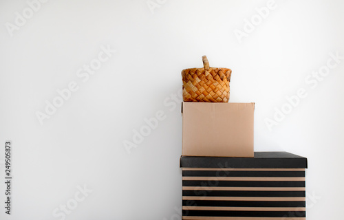 a pyramid of boxes and a bast-basket against a white wall