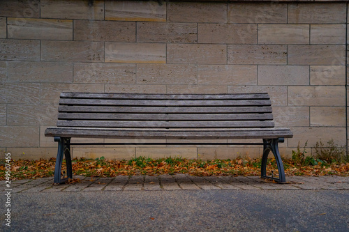 old wooden bench in the city heart of berlin germany, isolated bench in front of a stone wall 