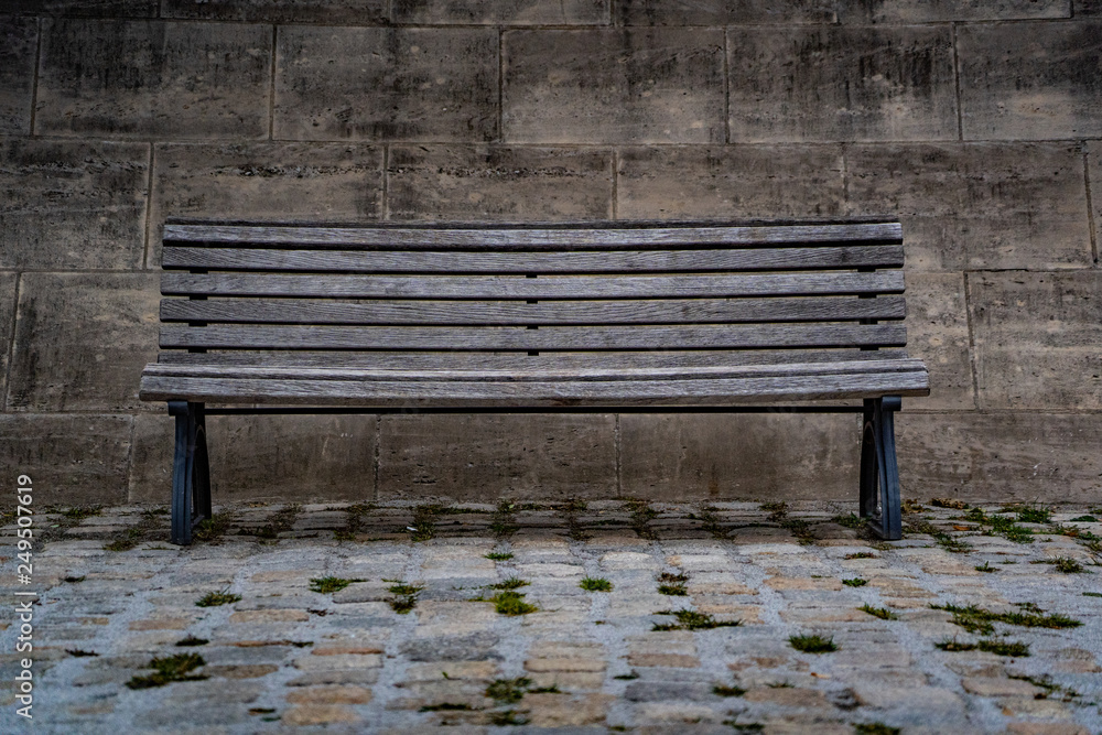 old wooden bench in the city heart of berlin germany, isolated bench in front of a stone wall old wooden bench in the city heart of berlin germany, isolated bench in front of a stone wall