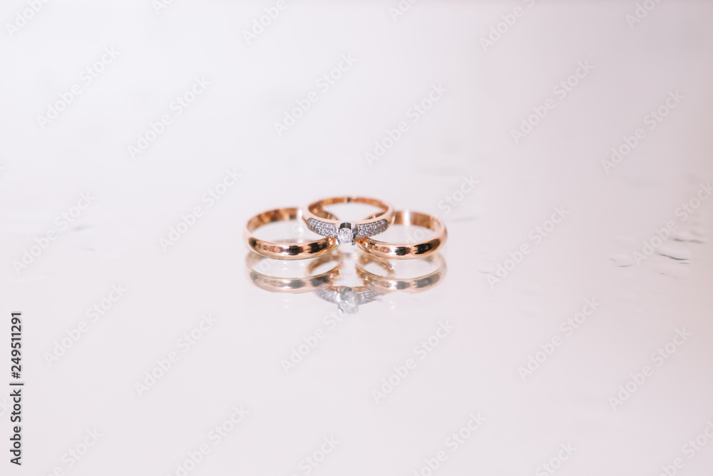 3 wedding gold rings on the white background glass with water drops . Wedding. Diamonds. 3 wedding gold rings on the white background glass with water drops . Wedding. Diamonds.