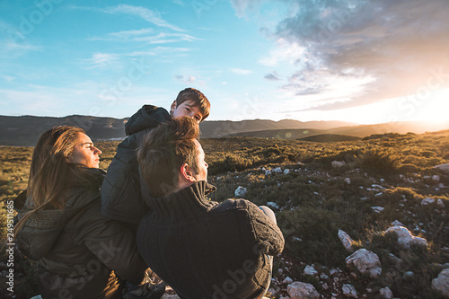 Family watching a sunset on the mountain. Couple with son with happy open arms. Concept of freedom