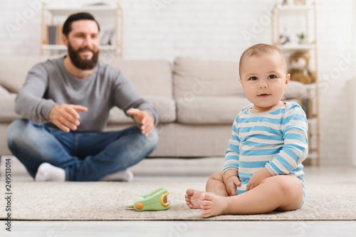 Father playing with his baby son on floor at home