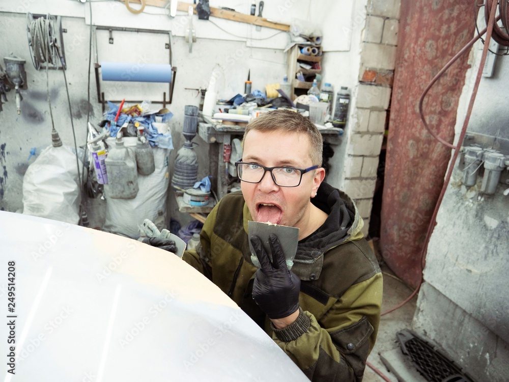 cute guy with glasses putty a car hood section of a garage in black gloves cute guy with glasses putty a car hood section of a garage in black gloves