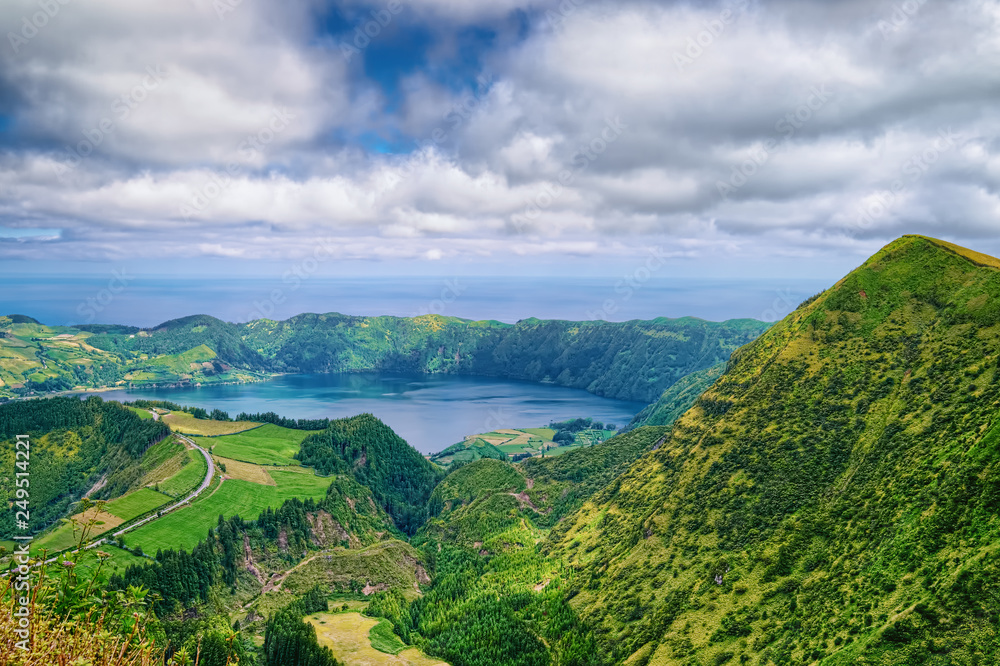 Lake in wide volcanic caldera, called Lagoa Azul in Portuguese, surrounded by green mountains of Sete Cidades, located on Sao Miguel island of Azores, Portugal.