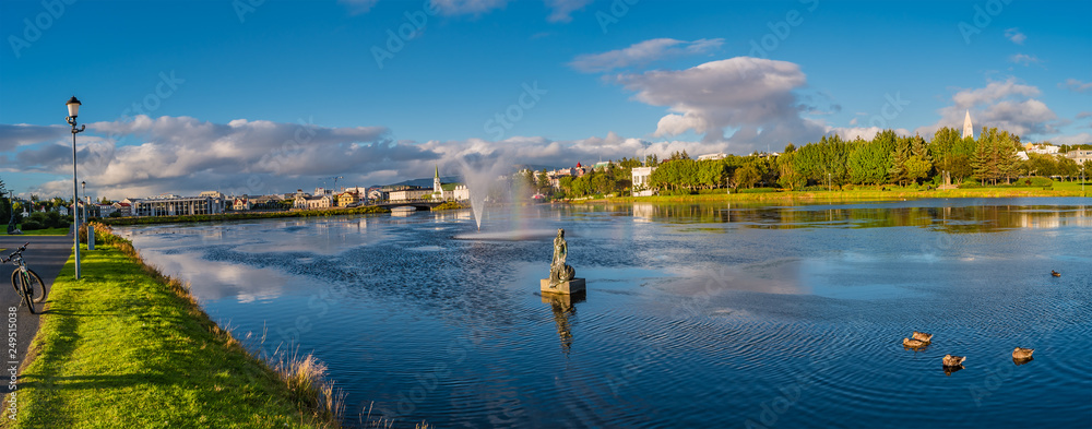 Panoramic view of Reykjavik downtown with lake on Iceland during sunset with rainbow, summer time - obrazy, fototapety, plakaty 