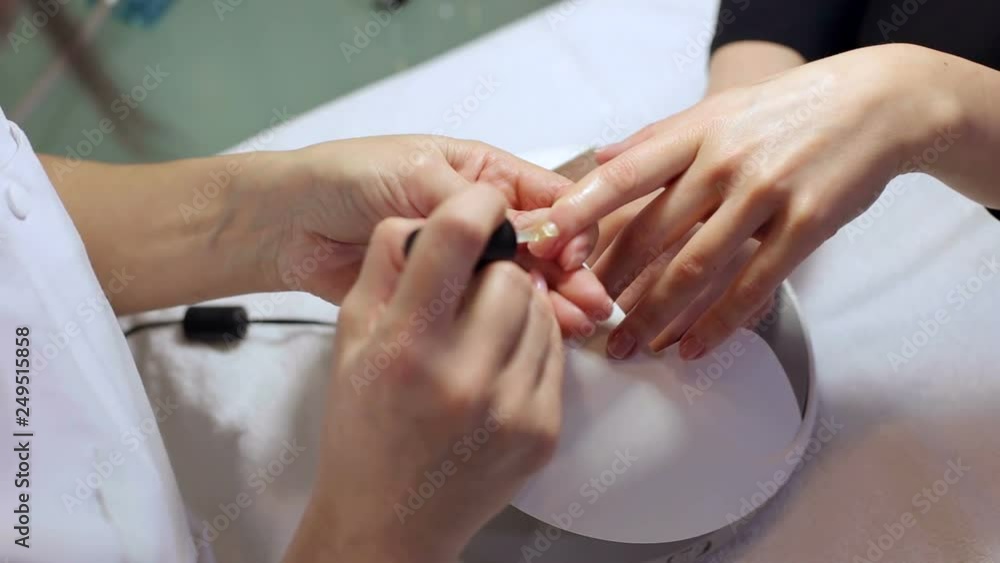 Girl paint nails in the salon of manicure, close-up. Master applies varnish on nails in manicure salon. Woman getting nail manicure in salon. Care for hands. Girl paint nails in the salon of manicure, close-up. Master applies varnish on nails in manicure salon. Woman getting nail manicure in salon. Care for hands.
