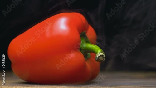 sweet red bell pepper or capsicum is on the table in cold, steam from frost in slow motion, cloese up photo