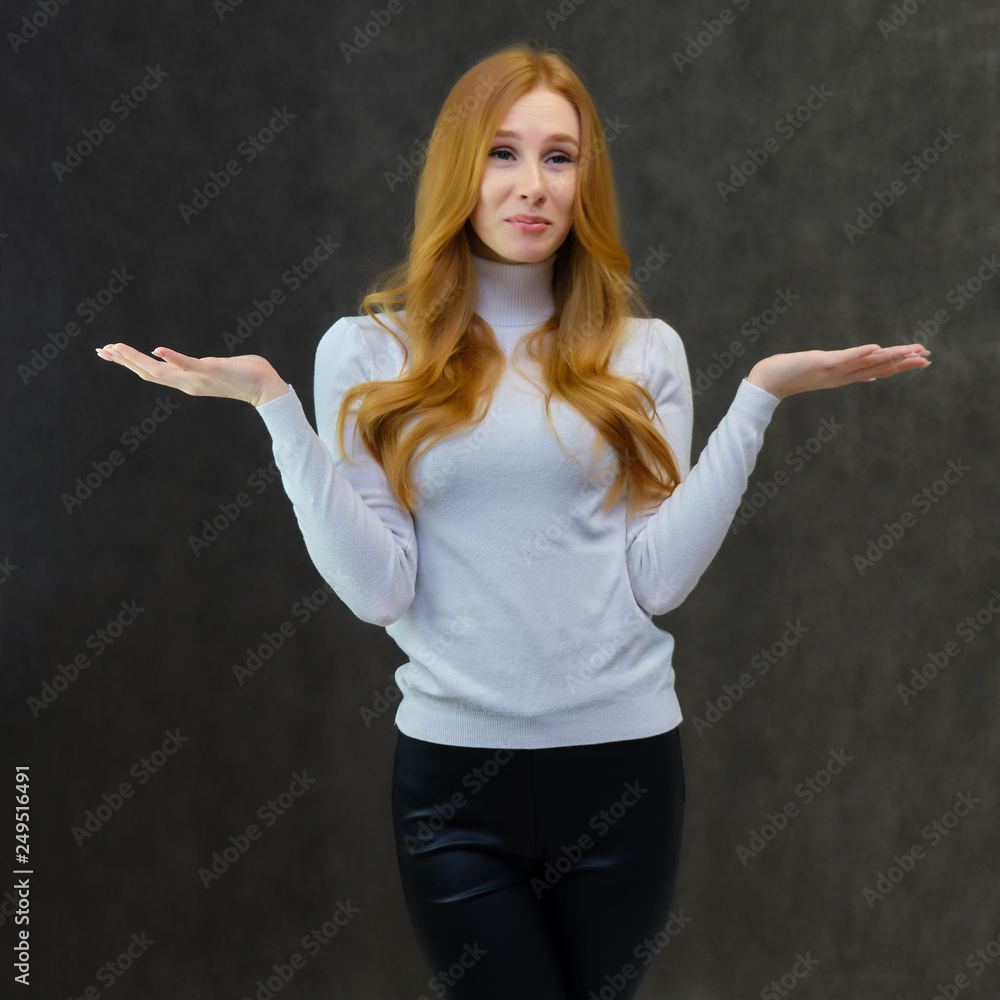 Concept portrait of a cute beautiful red-haired girl talking on a gray background in the studio. Concept portrait of a cute beautiful red-haired girl talking on a gray background in the studio.