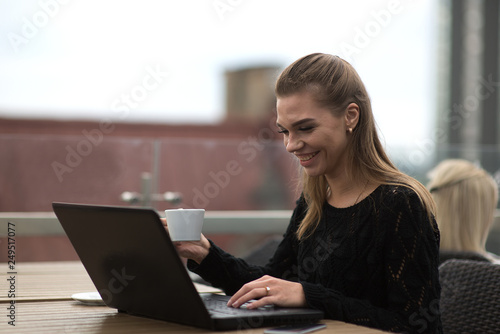 Young beautiful woman using laptop and drinking coffee