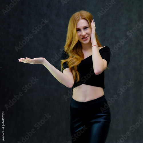 Concept portrait of a cute beautiful red-haired girl talking on a gray background in the studio